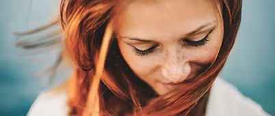 A woman with red hair looking down and smiling