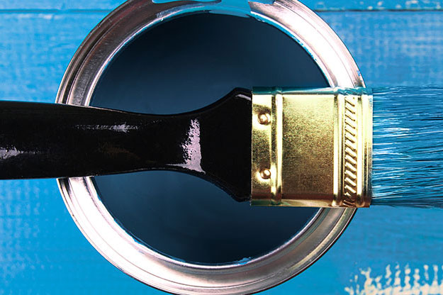 A paintbrush sat on a tin of blue paint