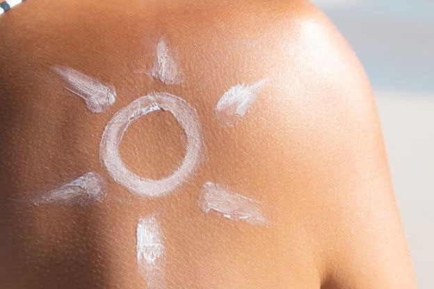 A sun drawn in suncream on a tanned shoulder