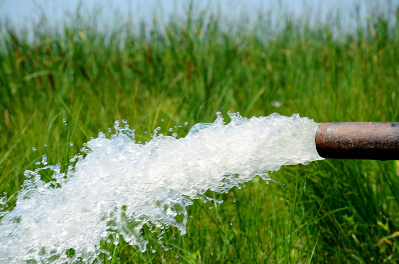 A man catching a stream of water in his hand in the sunset