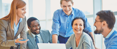 A diverse group of coworkers around a computer laughing
